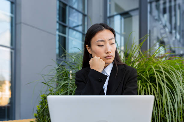 istock Sad and anxious Asian student, received disappointing news about entering university and college, sitting on a bench with a laptop 1368228598
