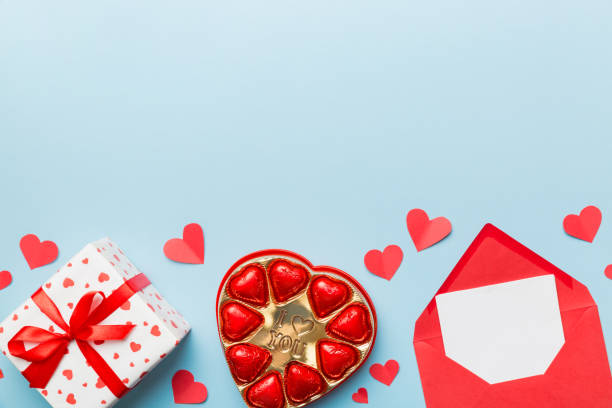 istock Envelope on colored background for Valentine Day with gift box and chocolate. Heart shaped with gift box of chocolates top view with copy space 1368228882