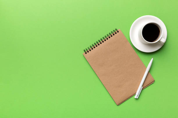 istock Modern office desk table with notebook and other supplies with cup of coffee. Blank notebook page for you design. Top view, flat lay 1368228934