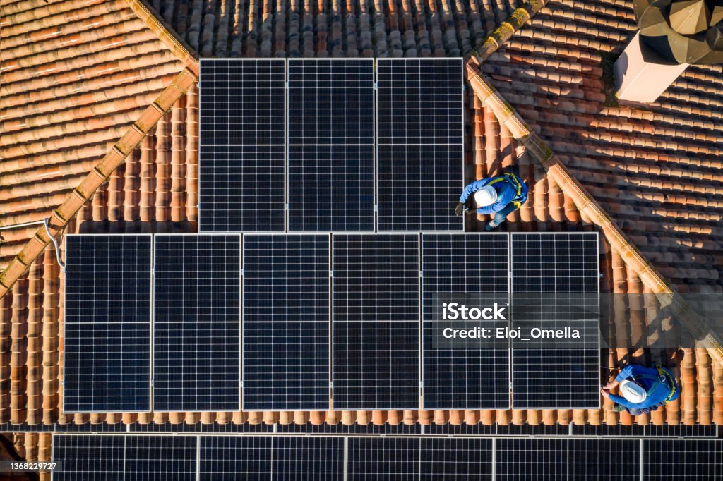 aerial view of Two workers installing solar panels on a rooftop aerial view of Two workers installing solar panels on a house roof Solar Panel Stock Photo