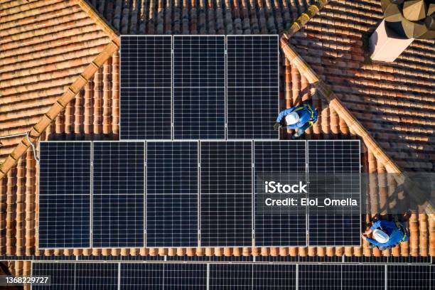 Aerial View Of Two Workers Installing Solar Panels On A Rooftop Stock Photo - Download Image Now