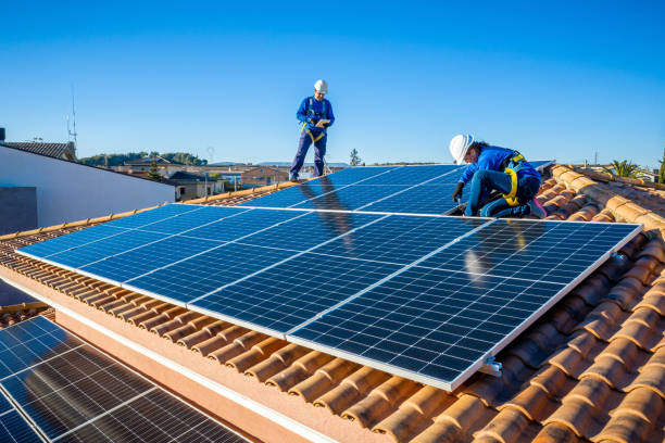 Male and female workers installing solar panels in a roof