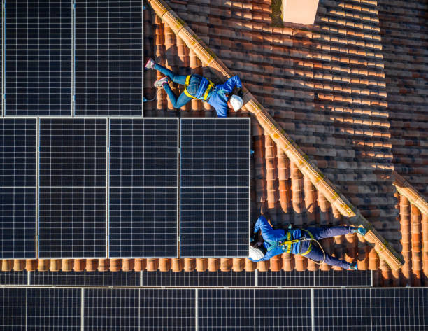 dois trabalhadores profissionais instalando painéis solares deitados no telhado de uma casa. vista aérea - overhead wires - fotografias e filmes do acervo