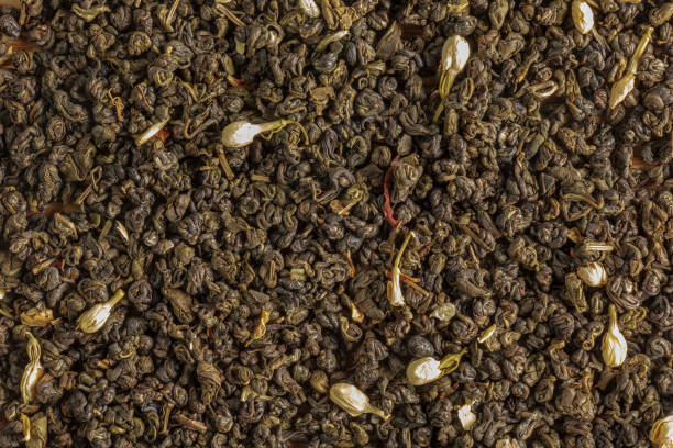зеленый чай с цветками и бутонами жасмина. фон и текстура сухого зеленого чая - jasmine tea leaf dry green tea стоковые фото и изображения