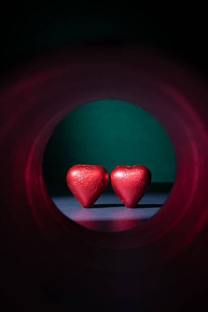 Concept of heart-shaped chocolate confections at the end of an illuminated tunnel. stock photo