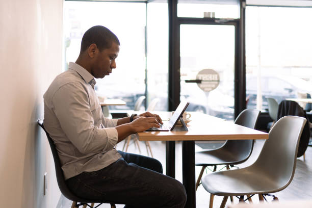 istock Black man using tablet and cellphone in a coffee shop 1368232521