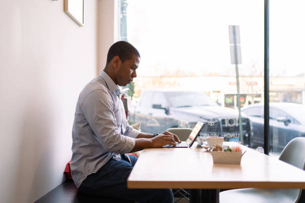 istock Black man using tablet and cellphone in a coffee shop 1368232530