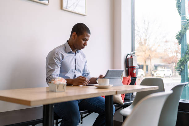 istock Black man using tablet and cellphone in a coffee shop 1368232536