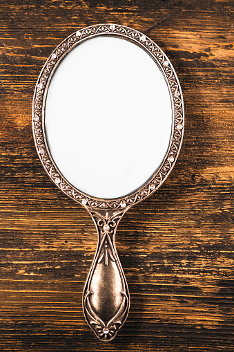 hand mirror on wooden wall