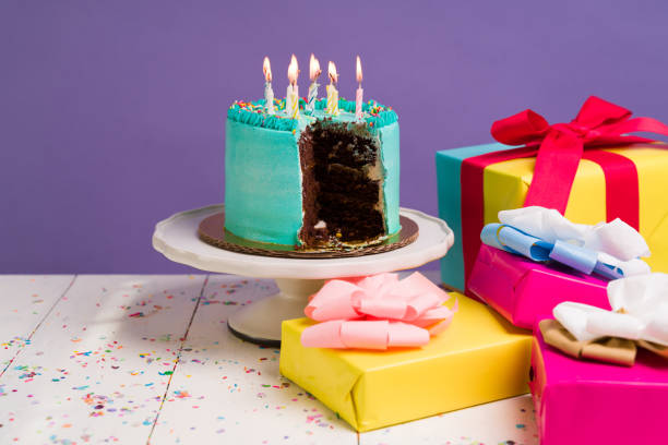 istock Many birthday gifts next to a cake 1368234065