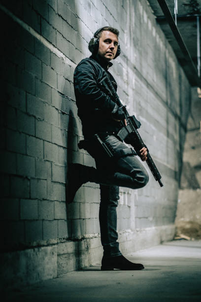istock Shooting preparations. Man holding M4 AR-15 rifle, posing to a camera. 1368236094