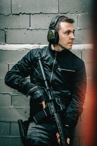 istock Shooting preparations. Man holding M4 AR-15 rifle, posing to a camera 1368236109
