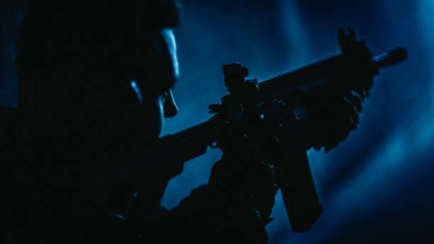 istock Sniper's training on a shooting range. M4 AR-15 rifle details. Looking over the shoulder, blue illuminations 1368236957