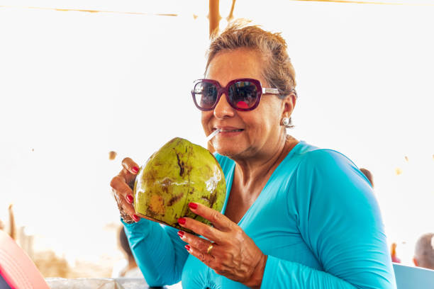 istock Attractive senior Hispanic woman drinking Coconut water 1368237340