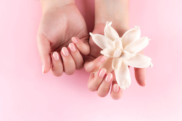 istock Female hands with natural nude nails and flower 1368237472
