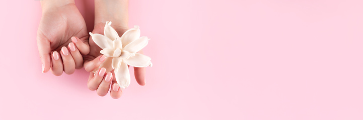 Manos femeninas con uñas nude naturales y cabecera de flores photo