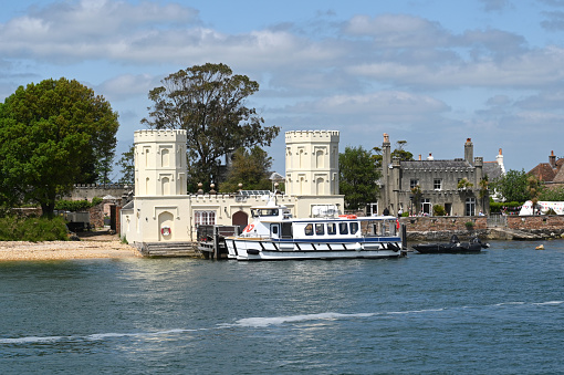 Poole Harbour, Dorset, England - June 2021: Small passenger ferry at the jetty for visitors to Brownsea Island, photographed from a passing boat. The island is a wildlife reserve.