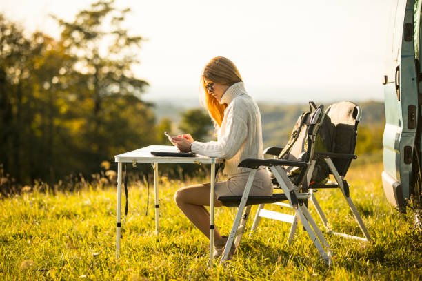 jovem usando celular enquanto acampava em viagem de estrada com motor home - mobile home vehicle trailer motor home isolated - fotografias e filmes do acervo