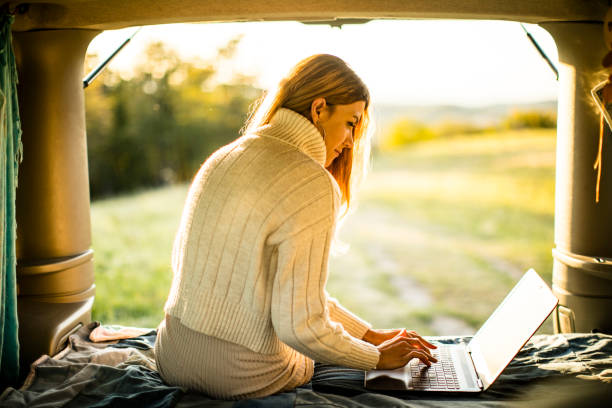 istock Back Lit Young Woman Using Laptop on Bed in Camper Van 1368238977