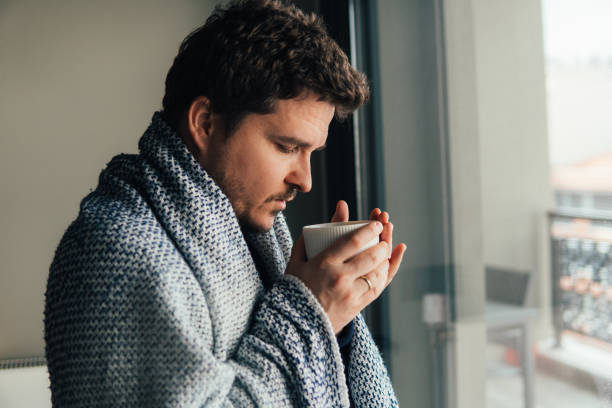 istock Man with blanket drinking coffee on cold winter morning 1368239190