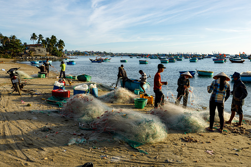 Mui Ne, Binh Thuan, Vietnam - December 22, 2019: Fisherman from Mui Ne in vietnam are repairing a fishing net