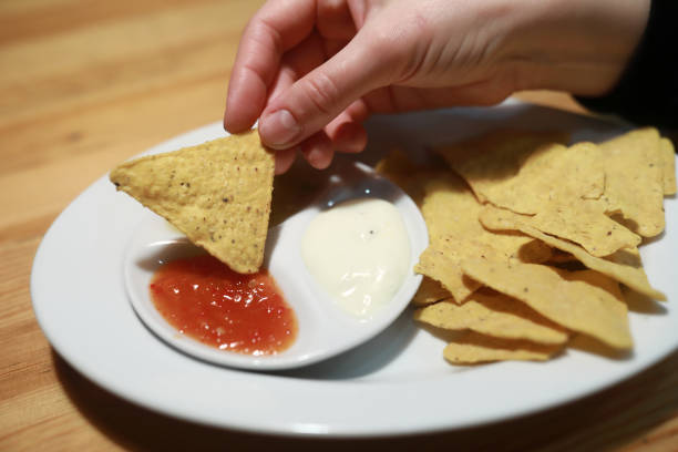 istock Person dipping nachos in tomato sauce 1368242676