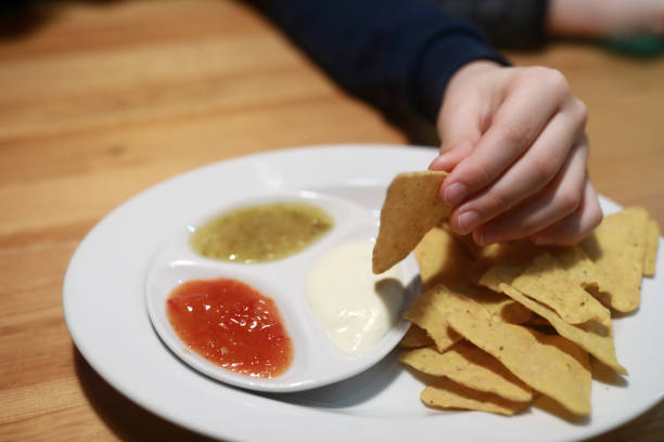 istock Person dipping nachos in sauce 1368242677
