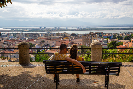 Cagliari,Sardinia.Italy 09 September 2021:A couple is sitting on a bench looking at the panoramic view of the city of Cagliari