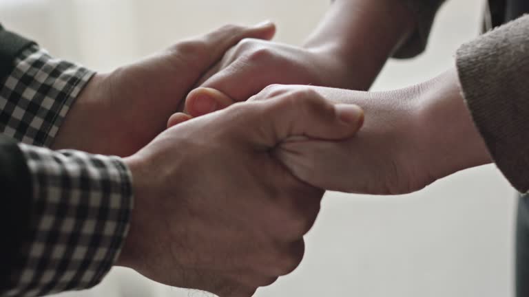 Crop view in close-up of man and woman holding hands with love standing in front of each other