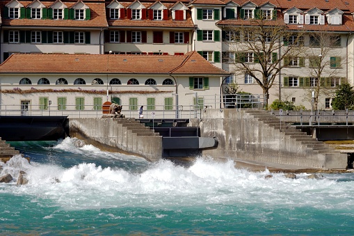 Floodgates or flood locks on the river Aare in Bern, Switzerland. They regulate the water flow. There are historic residential houses built along the riverbank.