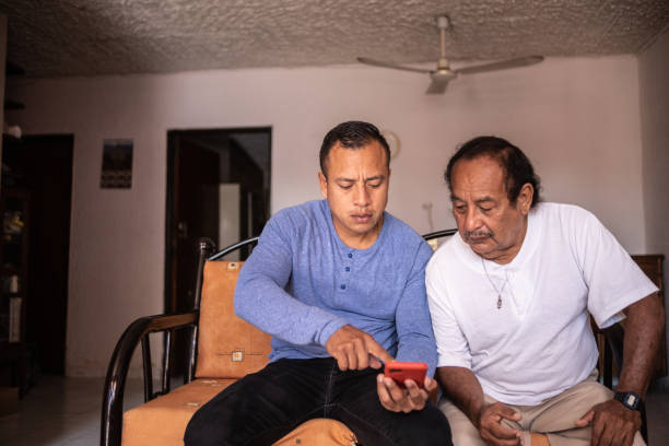 istock Son helping his father using a mobile phone at home 1368249718