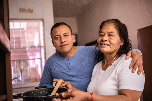 Portrait of latin mother and son cooking at home