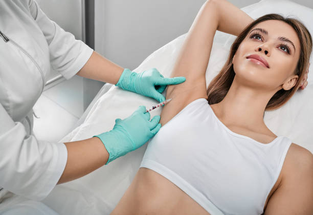 Underarm hyperhidrosis treatment. Armpit injections to prevent excessive sweating for female patient with beautician at cosmetology stock photo