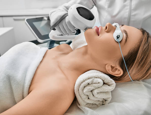 Cosmetologist using IPL apparatus treats skin of female patient's face Cosmetologist using IPL apparatus treats skin of female patient's face