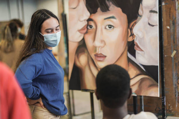 istock Young multiracial students doing art paint together at university school class while wearing safety face masks for coronavirus outbreak 1368252336