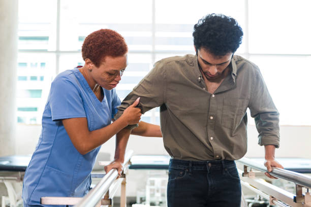 istock Physical therapist helps male patient use parallel bars 1368252383