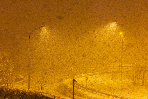 In the night, snowfall under streetlights