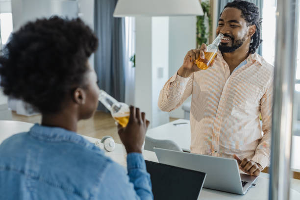 un couple afro-américain boit de la bière après le travail à la maison - after work beautiful people beer beer bottle photos et images de collection