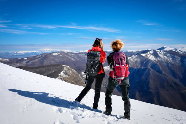 istock Women hikers explore the snow-capped mountain peaks. 1368254398