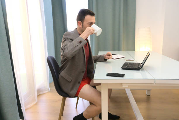 istock Sophisticated man in blazer and red underwear working from home drinking coffee from mug 1368254700