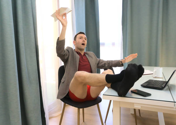 istock Happy slacker with feet on table flying a paper airplane while supposed to be working from home 1368254753