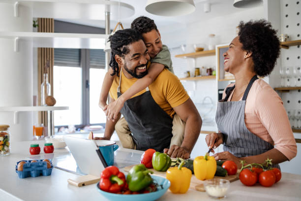 family preparing a healthy meal in the kitchen - two parent family couple family african ethnicity imagens e fotografias de stock