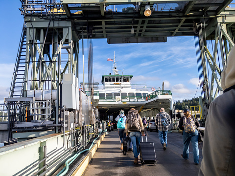 Friday Harbor, WA USA - circa November 2021: View of people lined up, waiting to board the Tillkum Washington State Ferry on a sunny day.