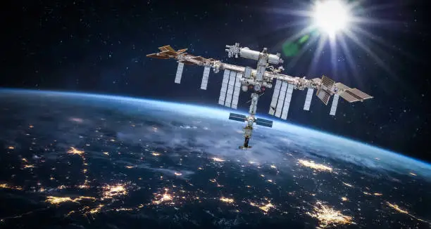 Photo of International space station in 2022 in outer space with Earth at night. ISS floating on orbit of nightly Earth planet. Elements of this image furnished by NASA