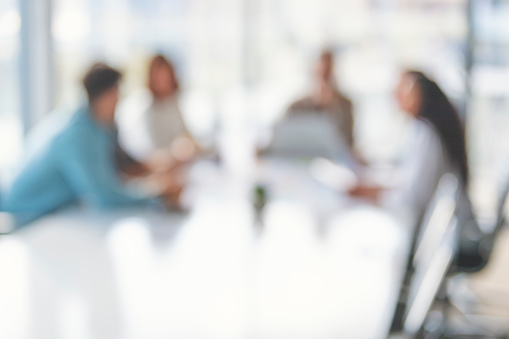 Defocussed image of Business people during a meeting. They are sitting in a board room, All are casually dressed.