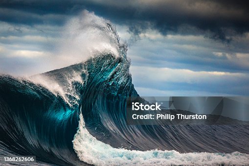istock Tall powerful cross ocean wave breaking during a dark, stormy evening. 1368262606