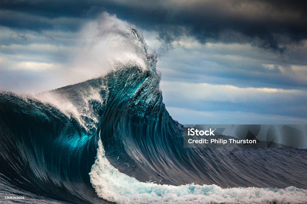 Tall powerful cross ocean wave breaking during a dark, stormy evening. Wave - Water Stock Photo