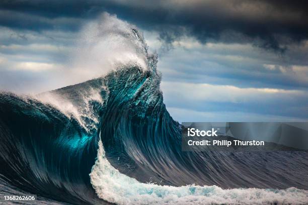 Tall Powerful Cross Ocean Wave Breaking During A Dark Stormy Evening Stock Photo - Download Image Now