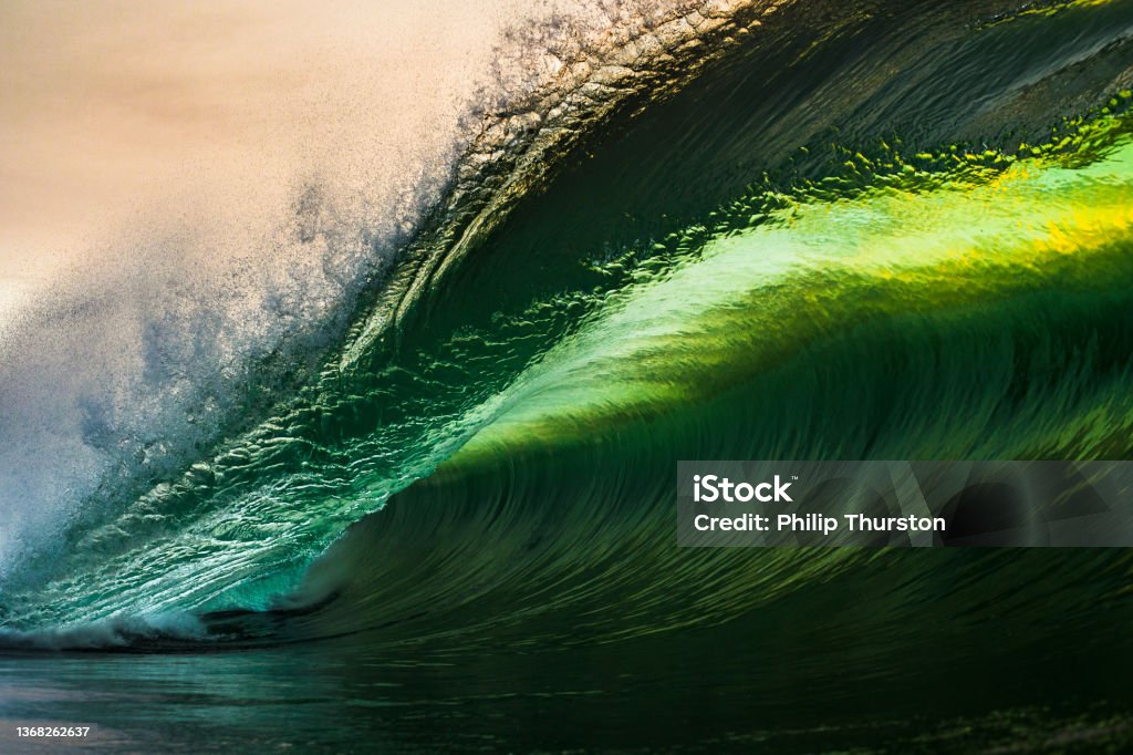 Powerful and beautiful sharp green and gold ocean wave breaking close up in shallow reef water Powerful and beautiful sharp green and gold ocean wave breaking close up in shallow reef water. Green Color Stock Photo