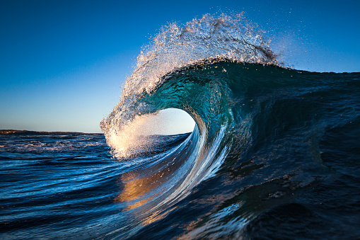 Blue ocean wave cresting in morning light